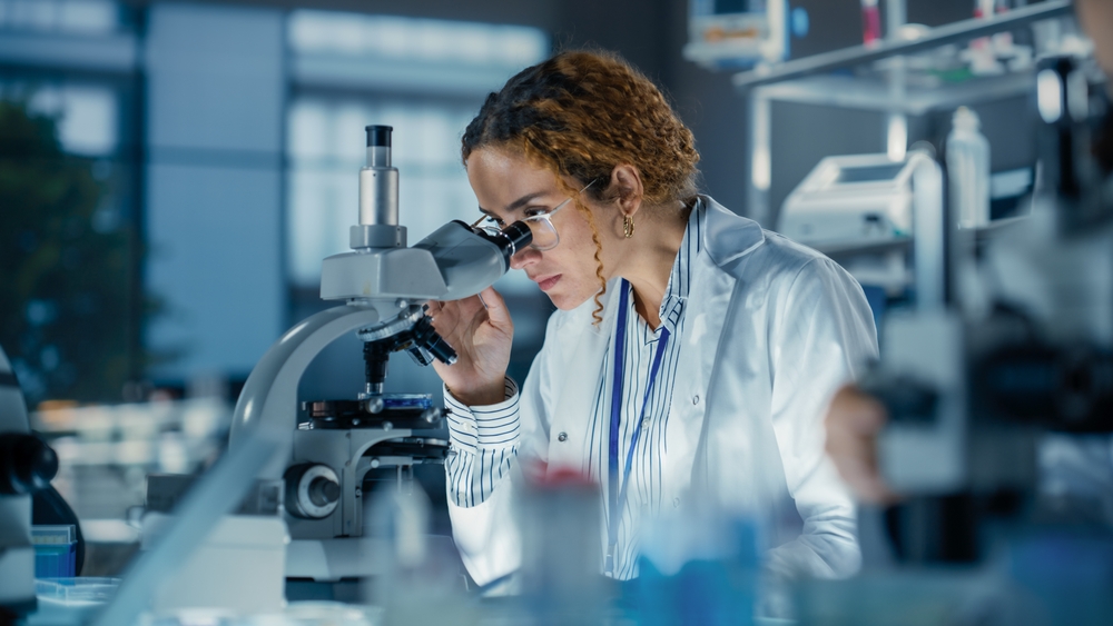 Cientifica observando principios activos en un microscopio de laboratorio